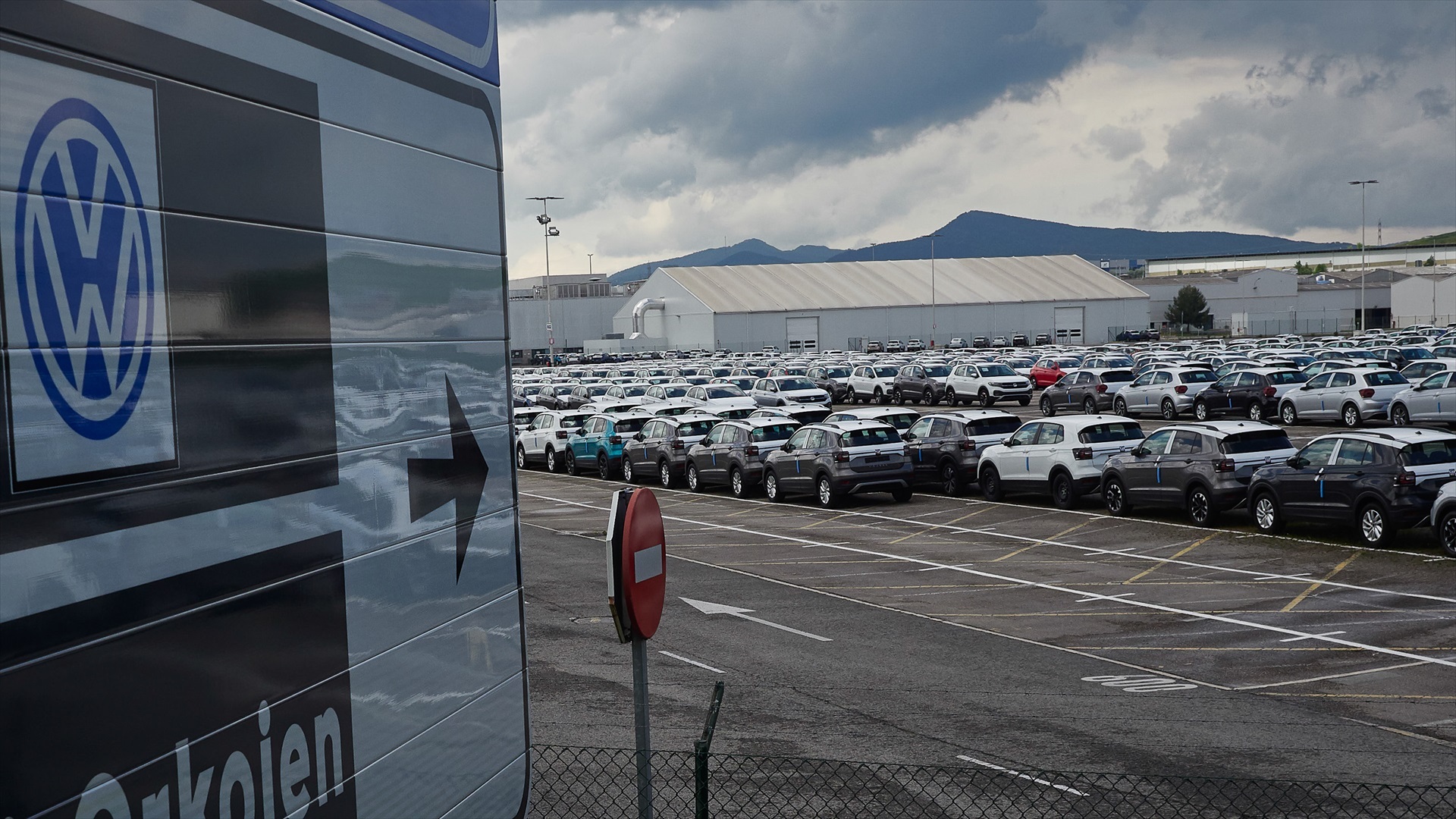 Gráfico financiero descendente y silueta de una fábrica de automóviles representando la crisis de previsiones de Volkswagen